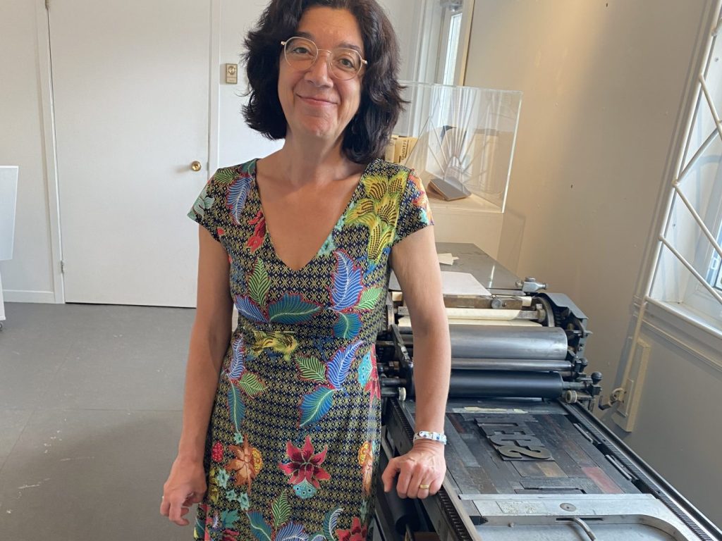 Une dame souriante en robe colorée se teint devant une presse