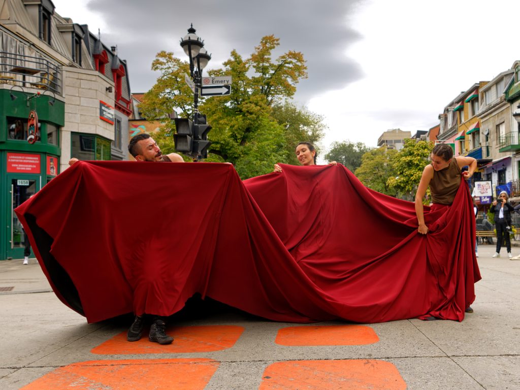 trois danseurs animent un grand drap rouge