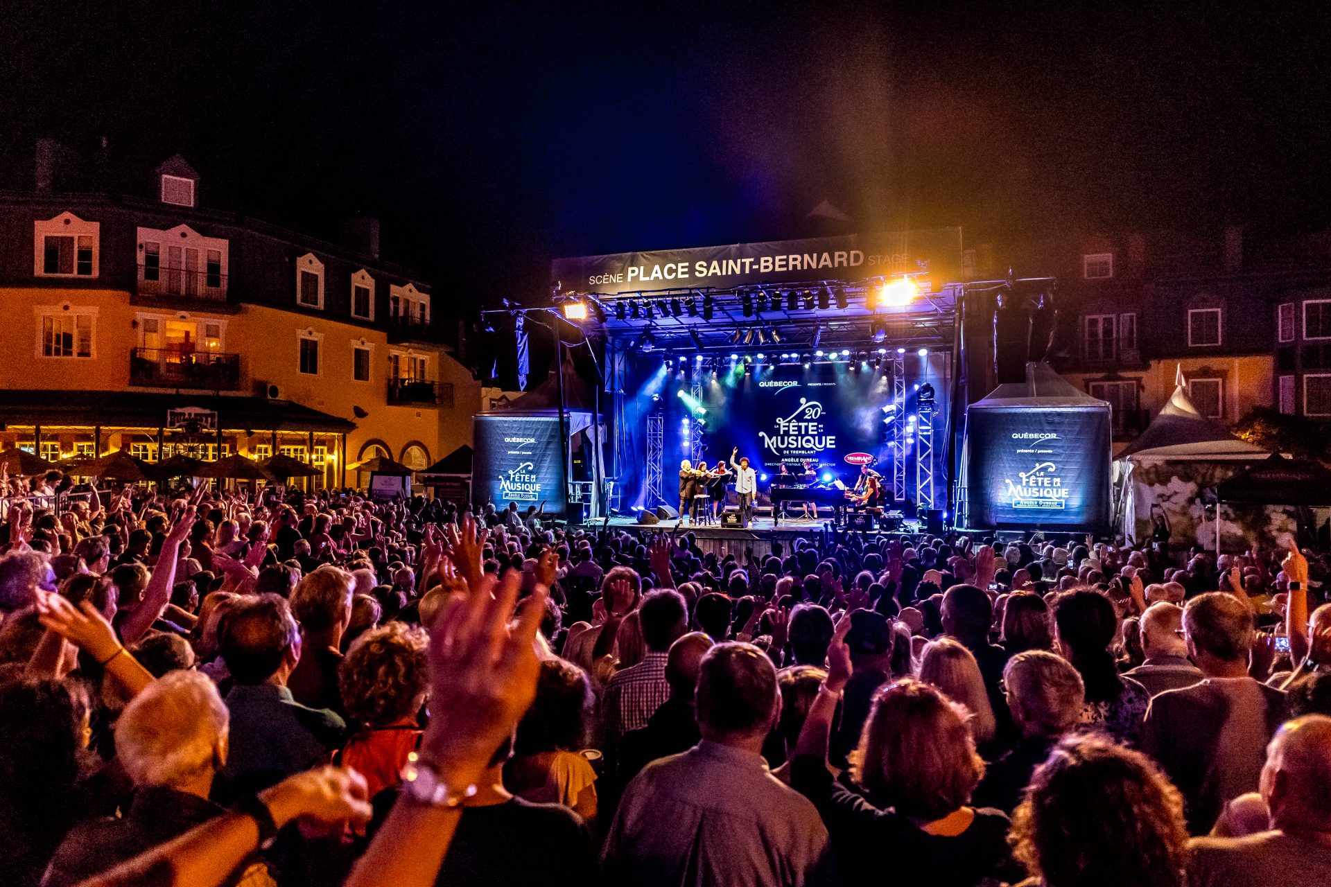 Une grande foule regarde un spectacle en soirée face à une scène dans le village piétonnier de Mont-Tremblant.