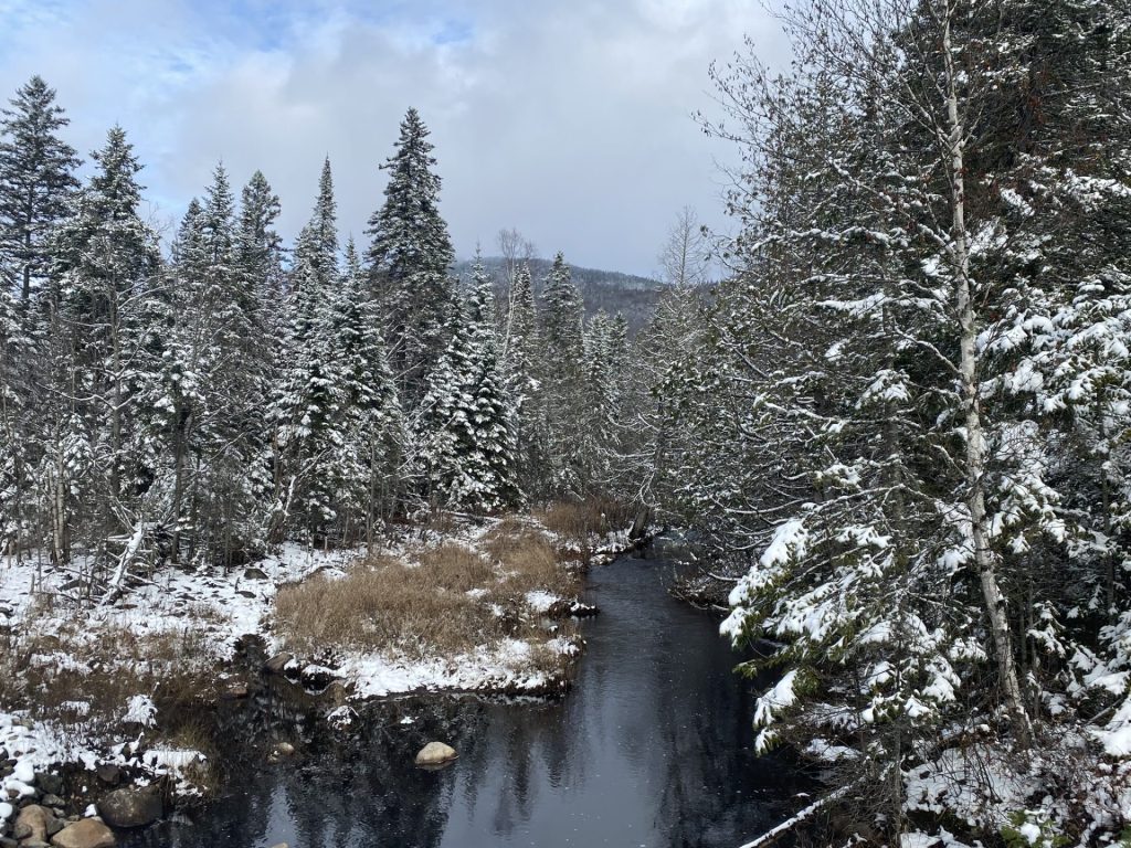 une montagne derrièrre un ruisseau après la première neige