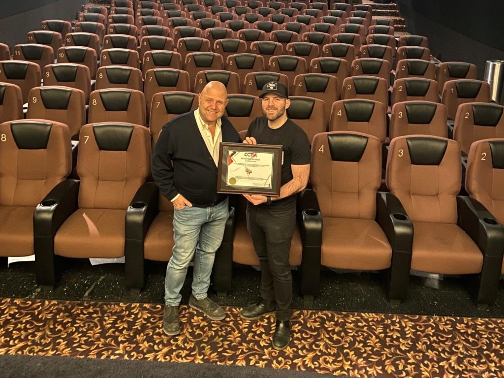 Deux hommes tiennent un eplaque dans une salle de cinéma